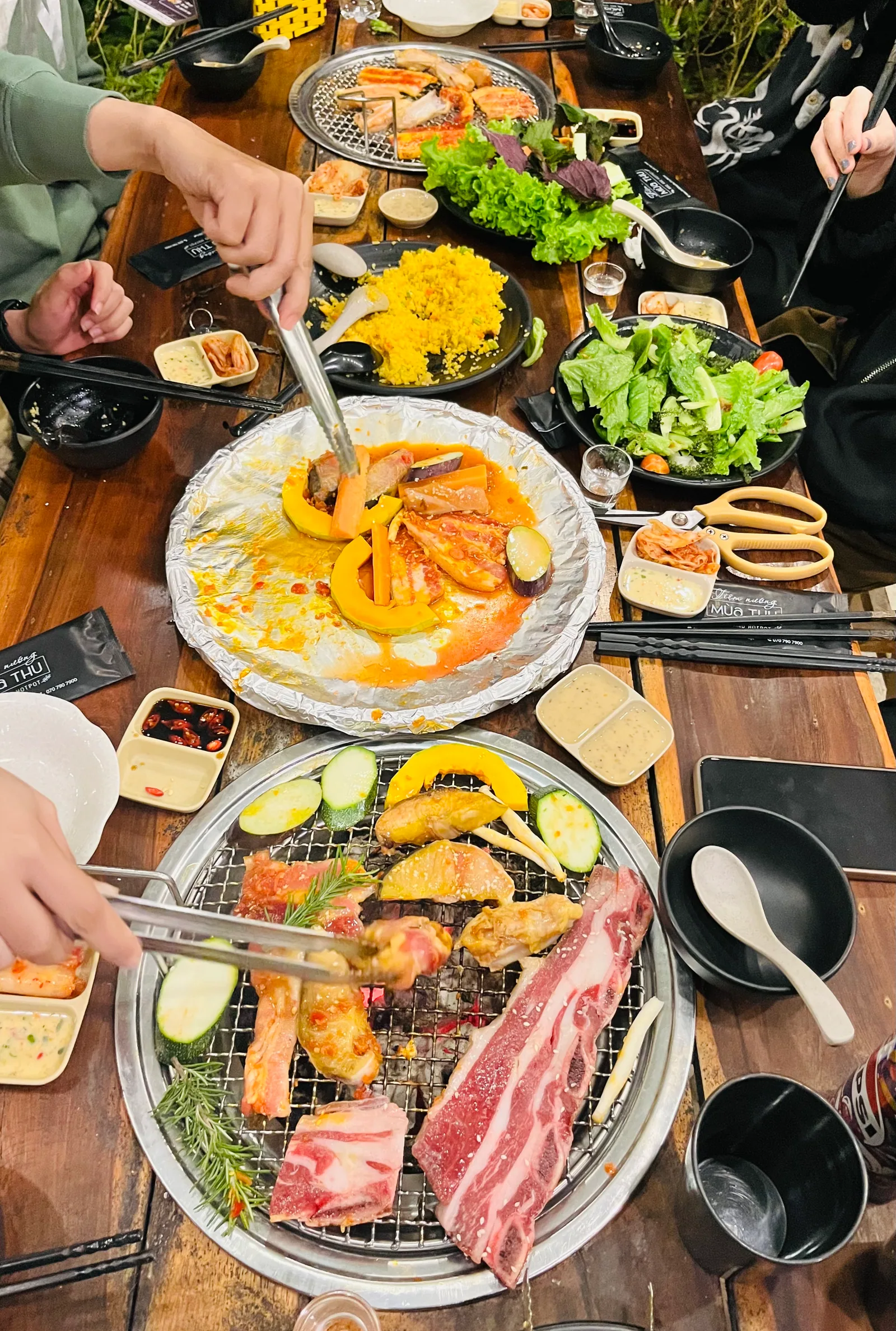 Góc nhìn dọc từ lối vào về phía bàn nướng có đèn vàng
